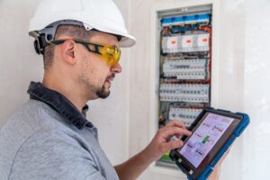 electrical technician looking focused while working switchboard with fuses